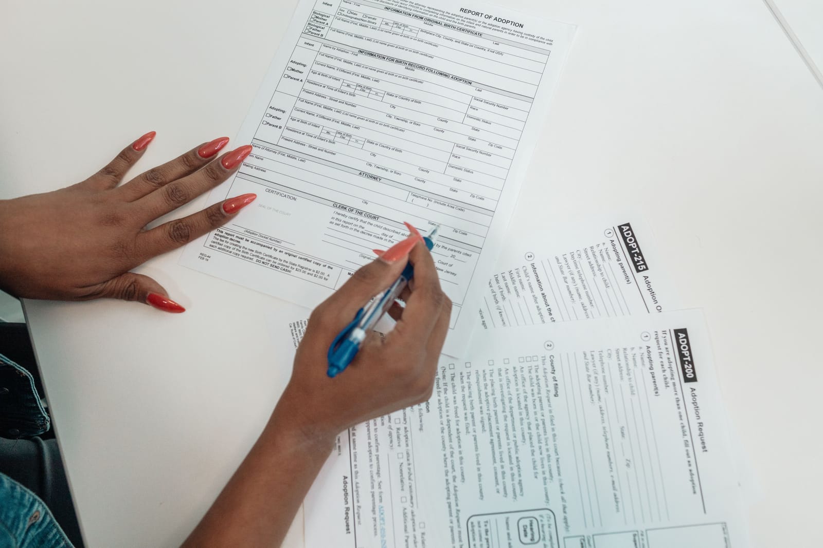 Een vrouw met rode nagels vult met een pen een formulier in aan een bureau, symbool voor het invullen van gezondheidsvragen bij een verzekeringsaanvraag